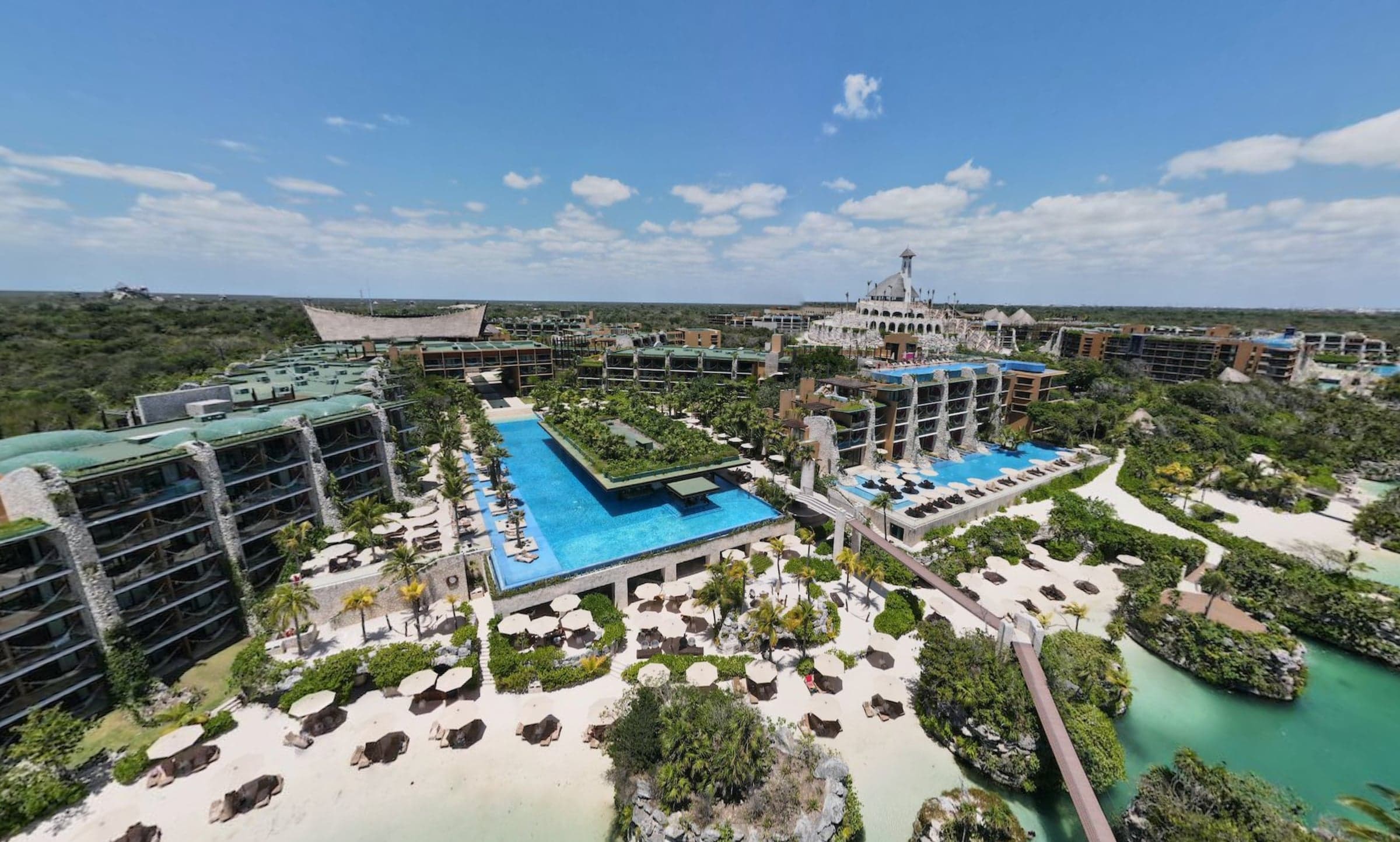 Aerial view of Hotel Xcaret Mexico — pools, beach, and the resort's signature tower